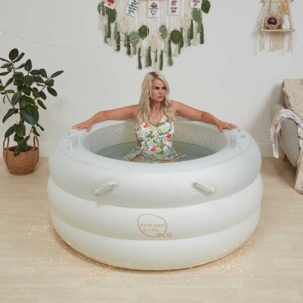 White birth pool in a box, with a woman sitting in pool