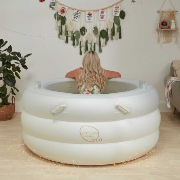 White birth pool in a box, with a woman in the pool facing away from camera